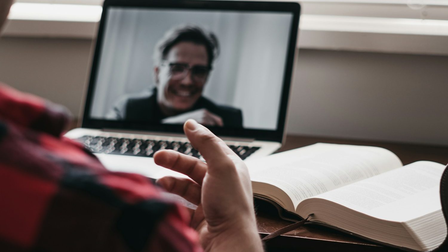 person in red and black plaid long sleeve shirt using black laptop computer